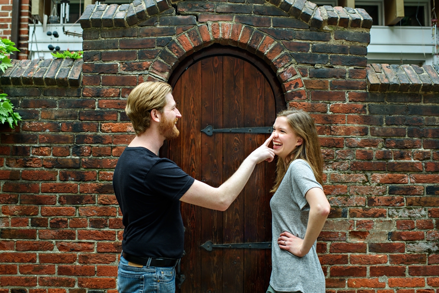 A cute couple standing in front of a brick wall in center city during philly engagement session.